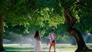 Eine Frau und eine Mann laufen im Sommer durch den Heidelberger Schlosspark. Am Donnerstag könnten wieder Temperatur-Rekorde geknackt werden.