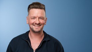 Der Sänger Ben Zucker lächelt in die Kamera.
