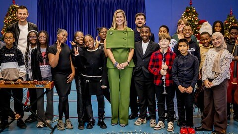 Königin Máxima der Niederlande steht zwischen Schülern mit Instrumenten, die eine Schulband haben.