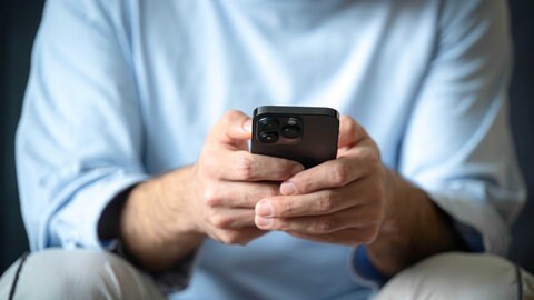 Ein Mann hält ein Handy in der Hand. 