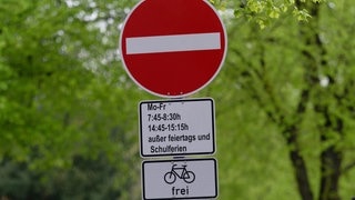 Ein Schild weist auf eine Sperrung einer Straße während der Bring- und Abholzeit einer in der Straße gelegenen Grundschule für den Autoverkehr.