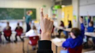 Ein Schüler meldet sich in einer vierten Klasse in einer Grundschule