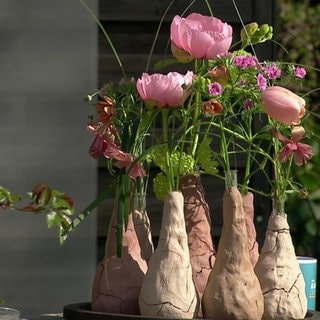 Kleine Tonvasen mit bunten Blüten.