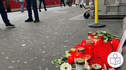 Auf einem Bahnsteig stehen rote Kerzen. Auf dem Boden liegen auch Blumen. Es ist ein Ort zum Gedenken an den getöteten Zug·begleiter Serkan Calar. Rechts das SWR Logo für Leichte Sprache.