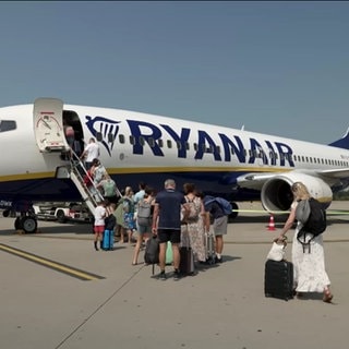 Menschen steigen in ein Flugzeug ein.