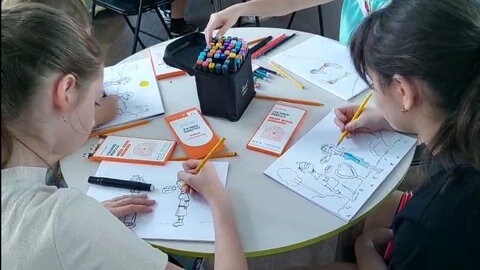 Johannes Kolz mit Kindern und Jugendlichen bei einem Zeichenkurs in einem Klassenzimmer in Isjum. 