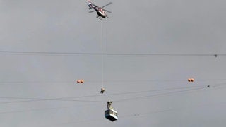 Ein Retter seilt sich aus einem Hubschrauber ab zur Karrenseilbahn.