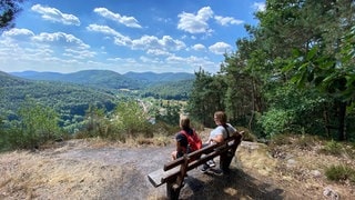 Menschen wandern in der Pfalz und blicken über den Pfälzerwald.