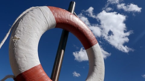 Ein Rettungsring hängt im Sommer am Rand eines Badegwässers. 