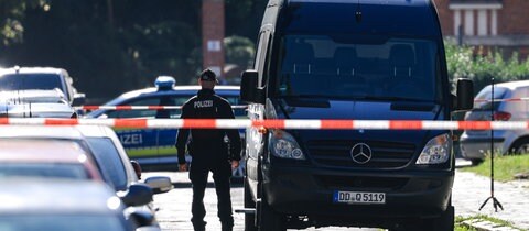 Ein Kastenwagen der Polizei mit einem Ermittler und Polizeiabsperrband (Symbolbild). Ende August hat ein Bauhof-Mitarbeiter in Bonladen-Filderstadt eine Leiche gefunden. Die konnte mittlerweile identifiziert werden.