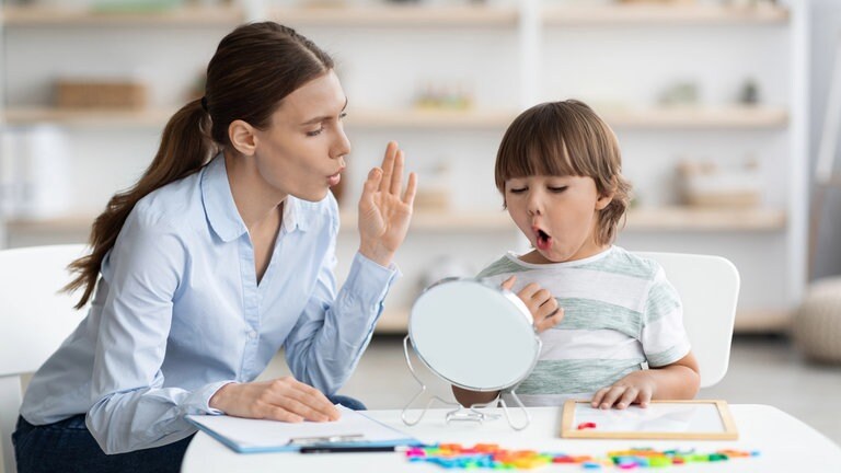 Kleiner Junge macht unter Anleitung einer Logopädin eine Sprechübung: Die Zahl der Kinder mit Sprachentwicklungsstörung steigt. Von Logopädie können aber auch Schlaganfall-Betroffene, Demenz-Erkrankte und sogar Säuglinge mit Fütterstörung profitieren.