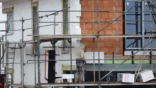 (Symbolbild) Ein Handwerker bringt Dämmmaterial an eine Hauswand ein. Eine Plattform aus Karlsruhe soll energetische Sanierung in Zukunft einfacher und schneller machen.