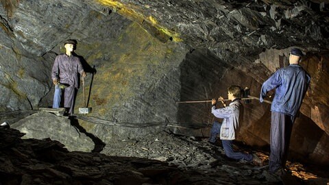 In den ehemaligen Schiefergruben im Bergwerk sind mehrere Bergbaufiguren aufgestellt. Sie halten Werkzeuge zum Abbauen von Schiefer in den Händen.