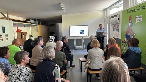Rund 20 Teilnehmer sitzen in einem Raum auf dem Verkehrsübungsplatz in Friedrichshafen. Beim Fahrsicherheitstraining in Friedrichshafen wurde ihnen alles rund ums Pedelec gezeigt.