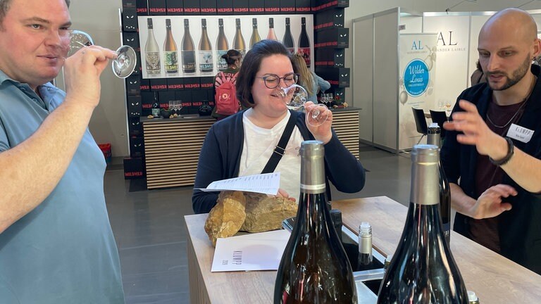 Zwei Menschen probieren auf der Fachmesse Eurovino in Karlsruhe am Stand vom Bioweingut Klumpp Wein.