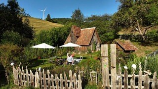 Anita Aberle-Schwenk steht in ihrem Bauerngarten Chritsleshof in Schramberg. Im Hintergrund sind Windräder zu sehen.