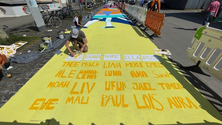 Entlang des Hafens in Konstanz sind bunte Bilder aufgemalt, man sieht sportliche Motive wie Bälle.