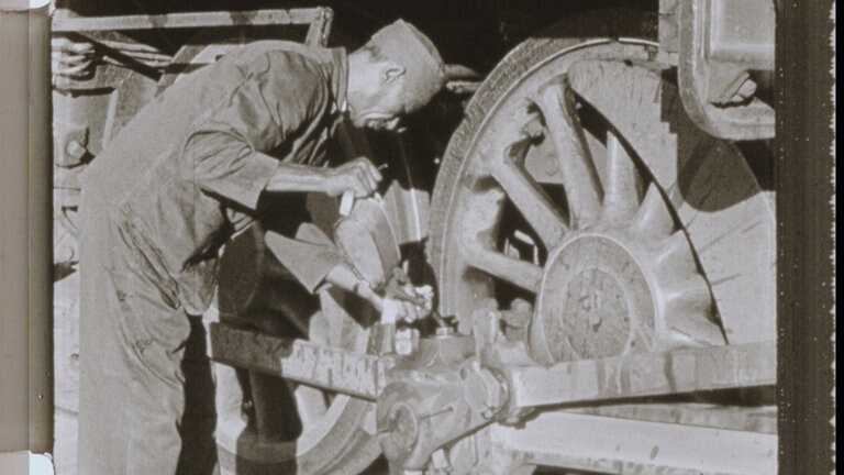 Bild aus einem 80 Jahre alten Film über die Sudanesische Eisenbahn. Bei einem Zwischenhalt ölt der Lokführer die Lager.