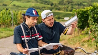 Szene aus den Fallers - Dominik Stricker und Alessio Hirschkorn bei einer Fahrradtour. Alessio hält die leere Trinkflasche hoch.