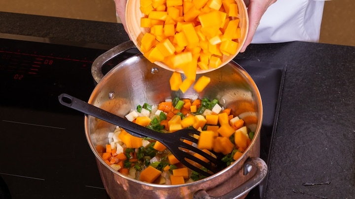 Die Kürbiswürfel werden in den Topf mit dem restlichen Gemüse gegeben. Egal ob Hokkaido- oder Butternut-Kürbis. Am Ende gibt es eine leckere Kürbissuppe.