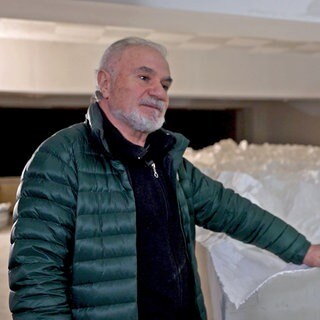 Panos Avramidis steht vor seiner weißen 3D-Nachbildung des Himalayas. Er trägt eine grüne Jacke und hält eine Hand auf der Nachbildung.
