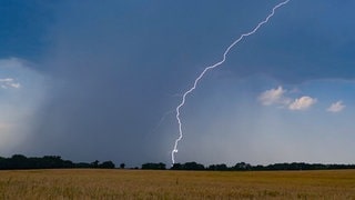 Ein Blitz leuchtet vor dunklen Gewitterwolken (Symbolbild) - nach der Hitze kommen Gewitter nach RLP