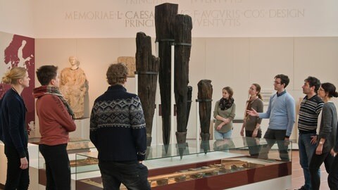Ein Gästeführer erklärt einer Gruppe im Rheinischen Landesmuseum Trier den Bau der Römerbrücke