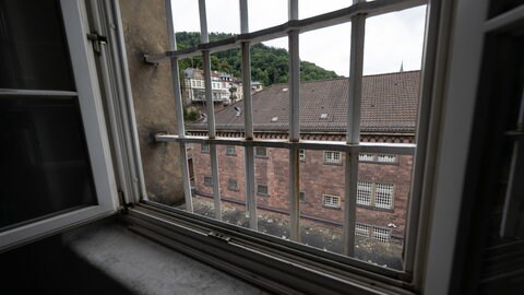 Ein Gebäude des Ex-Gefängnisses "Fauler Pelz" in der Heidelberger Altstadt ist durch ein vergittertes Fenster zu sehen. 