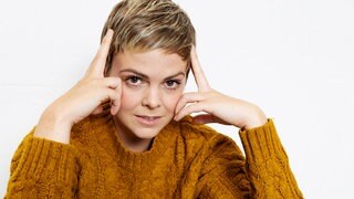 Jennifer Siemann im Interview: Die Schauspielerin schaut in die Kamera und stützt ihren Kopf mit beiden Händen ab.