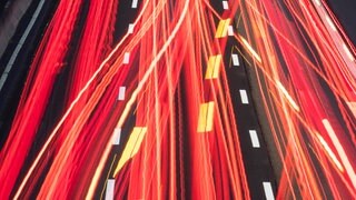 Die Scheinwerfer vorbeifahrender Fahrzeuge ziehen auf der Autobahn ihre Lichtspuren durch die hereinbrechende Dunkelheit 