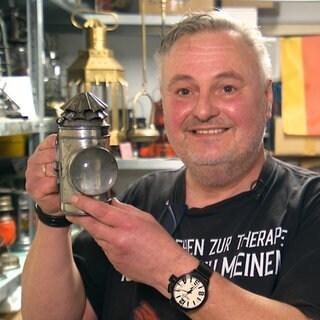 Jürgen Flieger steht mit einer Petroleumlampe in der Hand stolz vor der Kamera.