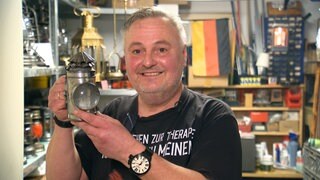 Jürgen Flieger steht mit einer Petroleumlampe in der Hand stolz vor der Kamera.