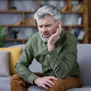 Mann hält sich schmerzend am Ohr