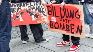 "Bildung statt Bomben": Demonstrationsteilnehmer halten Schilder in den Händen (Symbolbild). Bundesweit wird wieder gegen die Wehrpflicht demonstriert.
