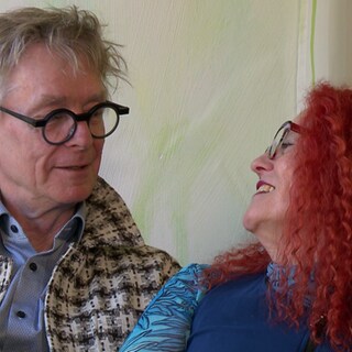 Diana Zöller und Edzard Schoppmann sitzen nah beieinander und lächeln. 