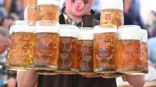 Ein Kellner trägt bei der Eröffnung des Cannstatter Wasen mehrere Bierkrüge. 