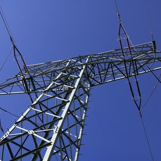 In mehrere Gemeinden (Otterberg-Otterbach, Weilerbach) im Kreis Kaiserslautern herrscht seit dem Vormittag Stromausfall. (Strommast vor blauem Himmel)