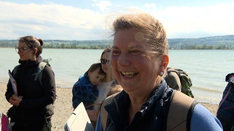 Eine lachende Frau vor einer Menschengruppe.