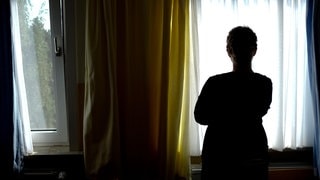 Frau als Schatten vor einem Fenster