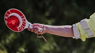Ein Polizist hält eine Kelle mit der Aufschrift "Halt Polizei" in der Hand (Symbolbild)
