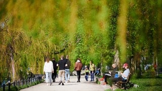 Menschen gehen am Landwehrkanal in Berlin in der Sonne spazieren.