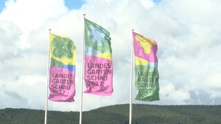 Landesgartenschau-Fahnen im Wind, dahinter bewaldete Berge