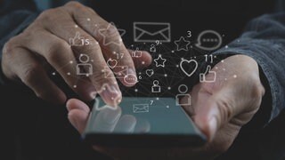 Ein digitales Hologramm mit Social Media Symbolen über einem Smartphone.