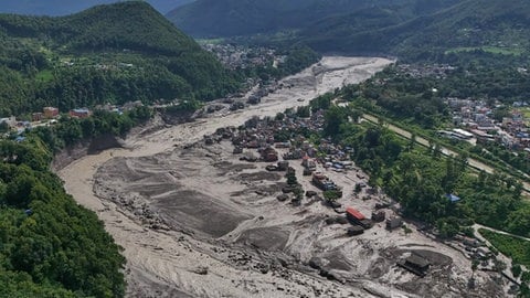 Nach Sturzfluten im nepalesischen Distrikt Nuwakot stehen beschädigte Häuser gefährlich nahe an den angeschwollenen, mit Treibgut verstopften Ufern des Trishuli-Flusses.