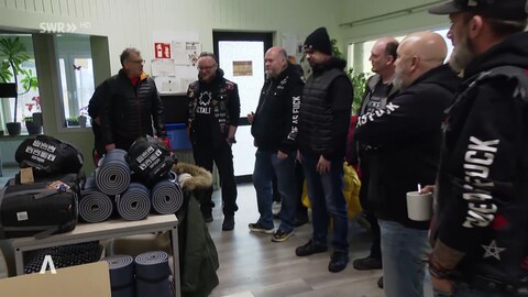 Die Rockergruppe steht im Kreis um die gesammelten Schlafsäcke