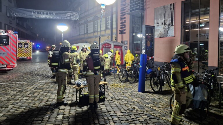 Einsatzkräfte von Feuerwehr und Rettungsdienst stehen in Schutzkleidung auf dem Münsterplatz in Konstanz.