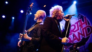 Die Band Manfred Manns Earth Band mit Musiker Robert Hard und Steve Kinch sind auf der Bühne, stehen Rücken an Rücken und singen