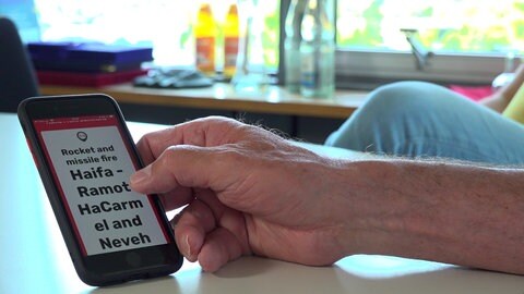 Der Tübinger Landrat Joachim Walter hält sein Handy in der Hand. Darauf hat er noch immer die App installiert, die ihn in Israel vor Reketenangriffen gewarnt hat.