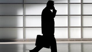 Silhouette eines Mannes mit Aktenkoffer telefoniert im Gehen
