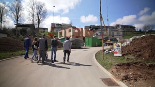 Fünf Menschen laufen die Straße zu ihrem neuen Baugebiet hoch.